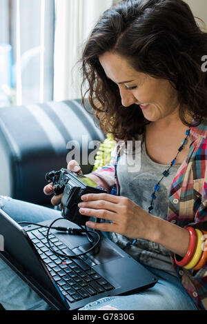 Jeune femme du téléchargement des photos de la caméra à l'appareil de stockage Banque D'Images