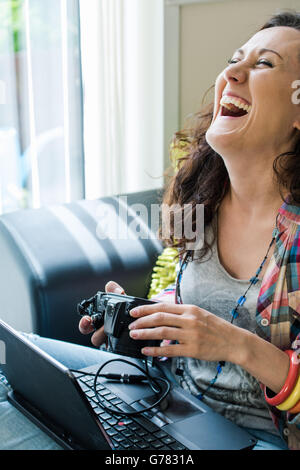 Jeune femme rire pendant la navigation sur l'appareil-photos Banque D'Images