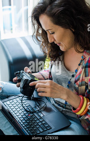 Jeune dame hipster télécharger photos de l'appareil en ordinateur portable Banque D'Images