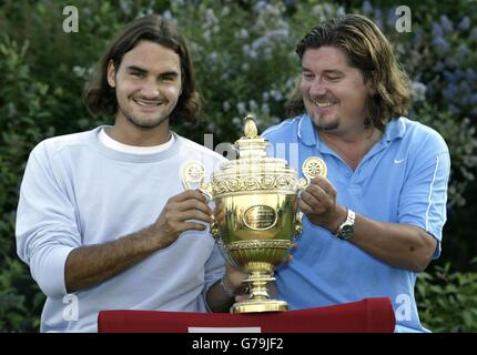 USAGE ÉDITORIAL SEULEMENT, PAS D'UTILISATION DE TÉLÉPHONE MOBILE Roger Federer de Suisse et son entraîneur Peter Lundgren (à droite) posent avec le trophée après sa victoire sur Mark Philippoussis d'Australie dans la finale masculine 7:6/6:2/7:6 aux Championnats de tennis de pelouse de toute l'Angleterre à Wimbledon. Banque D'Images