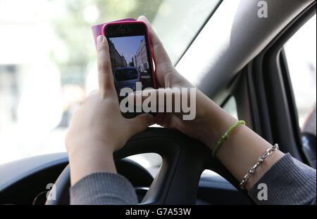 Stock moteur.PHOTO POSÉE PAR LE MODÈLE Une femme prend une photo sur son téléphone tout en conduisant. Banque D'Images