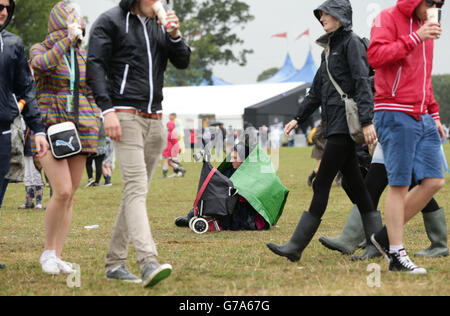 Un gardien de festival se tient à l'abri de la pluie pendant la deuxième journée du V Festival, à Hylands Park à Chelmsford, Essex. Banque D'Images