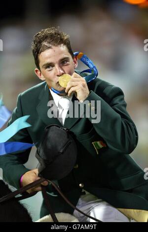 Cian O'Connor d'Irlande, à bord du Waterford Crystal, embrasse sa médaille d'or lors de la finale individuelle de saut de spectacle au centre équestre olympique près d'Athènes en Grèce. Banque D'Images