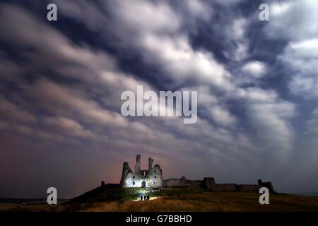 Les nuages s'enroulent au-dessus du château de Dunstanburgh dans le Northumberland, alors que les photographes attendent les lumières du nord très attendues (aurora) qui n'ont pas pu apparaître dans de nombreuses parties du Royaume-Uni. Banque D'Images