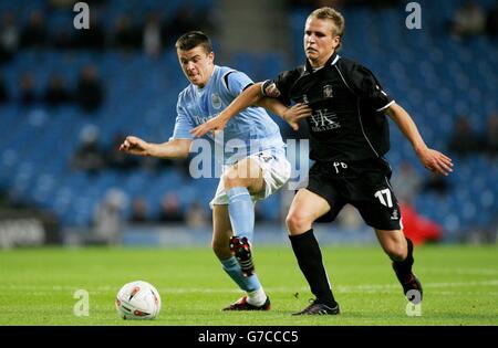 Joey Barton de Manchester City (à gauche) se trouve aux côtés de Nicky Rowe de Barnsley pour le ballon lors de leur deuxième match de la coupe Carling au City of Manchester Stadium, à Manchester. Banque D'Images