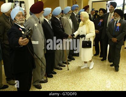 La reine Elizabeth II de Grande-Bretagne, accompagnée du duc d'Édimbourg (dos), salue les anciens combattants avec ses chaussures retirées, lors d'une visite à Gurdwara Sri Guru Singh Sabha (le temple sikh) à Hounslow, dans l'ouest de Londres. Le couple royal était au temple pour ouvrir une phase de développement de 2.5 millions. Banque D'Images