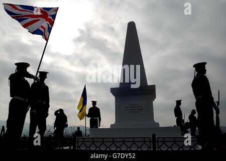 Les officiers de la marine ukrainienne détiennent des drapeaux britanniques et oukraniens à un service commémoratif situé à un monument britannique pour ceux qui ont perdu la vie à la bataille de Balaclava, le 150e anniversaire de la charge de la Brigade légère, Crimée, Ukraine. Banque D'Images