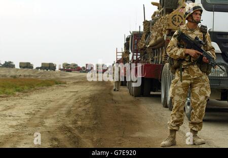 Un soldat britannique du 1er The Queen's Dragoon Guards marche le long d'un convoi de l'armée britannique qui se prépare à voyager la nuit, de Bassora pour rejoindre le groupe Black Watch Battle à Camp Dogwood, à 20 miles au sud-ouest de Bagdad. Banque D'Images