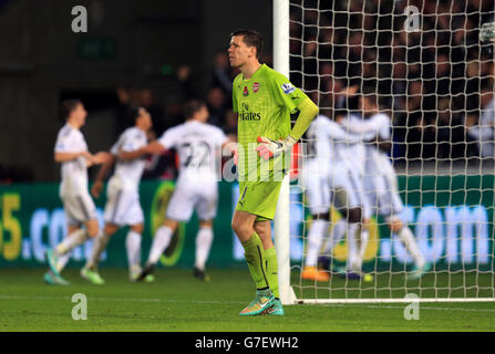 Wojciech Szczesny d'Arsenal est abattu après le Bafetimbi Gomis de Swansea City marque le deuxième but de son côté Banque D'Images