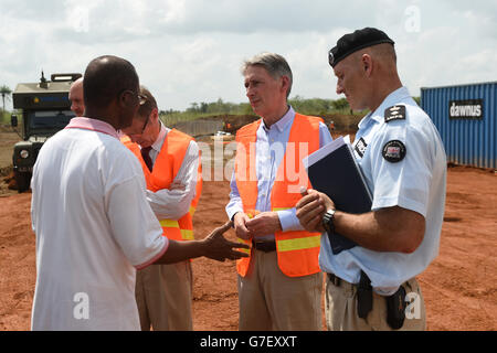 Le secrétaire aux Affaires étrangères Philip Hammond (au centre) s'entretient avec les habitants de la région lors de sa visite au nouveau centre de traitement d'Ebola en construction à Port Loko, en Sierra Leone. Banque D'Images