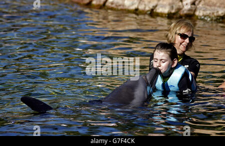 Maisy Gallagher-Horwood (gilet de sauvetage bleu) d'Oxford aime nager avec un dauphin lors du voyage caritatif DreamFlight à Discovery Cove à Orlando, en Floride. Banque D'Images