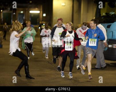 Des gens habillés de zombies chassent les participants lors d'une course de zombies au centre commercial Ealing Broadway dans l'ouest de Londres, pour recueillir de l'argent pour la charité locale The Log Cabin. Banque D'Images