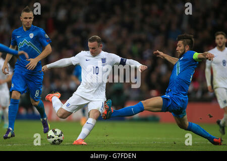 Wayne Rooney, en Angleterre, est tiré malgré les attentions de Bostjan Cesar (à droite), en Slovénie, lors du match de qualification de l'UEFA Euro 2016 Groupe E au stade Wembley, à Londres. Banque D'Images