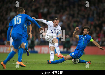 Wayne Rooney, en Angleterre, est tiré malgré les attentions de Bostjan Cesar (à droite), en Slovénie, lors du match de qualification de l'UEFA Euro 2016 Groupe E au stade Wembley, à Londres. Banque D'Images