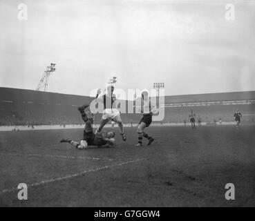 Le gardien de but de Wolverhampton Wanderers Malcolm Finlayson prend le ballon pendant qu'il fait une plongée spectaculaire aux pieds de West Ham United centre-avant Harry Obeney pendant le match de première division à Upton Park.Sur la droite se trouve West Ham juste en arrière George Showell. Banque D'Images