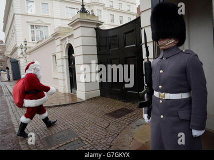 Un homme habillé comme Père Noël passe une garde à son arrivée au Palais St James, à Londres, où la princesse Royale a tenu une fête de Noël pour l'Association non oubliée. APPUYEZ SUR ASSOCIATION photo. Date de la photo: Jeudi 4 décembre 2014. L'association est un organisme de bienfaisance national triservice qui offre des divertissements, des loisirs et des loisirs pour les blessés, les blessés ou les malades en service et pour les hommes et les femmes ayant un handicap en service. Le crédit photo devrait se lire : Anthony Devlin/PA Wire Banque D'Images