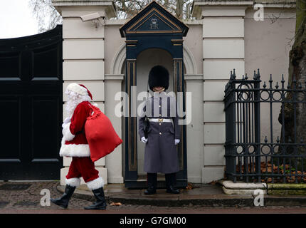 Un homme habillé comme Père Noël passe une garde à son arrivée au Palais St James, à Londres, où la princesse Royale a tenu une fête de Noël pour l'Association non oubliée. Banque D'Images