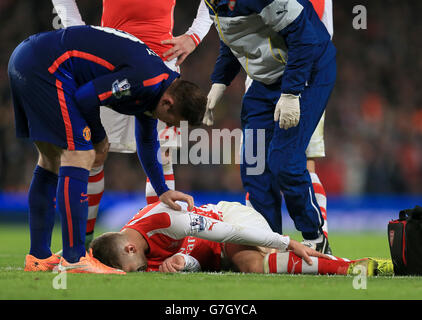 Football - Barclays Premier League - Arsenal / Manchester United - Emirates Stadium.Jack Wilshere d'Arsenal maintient sa cheville sur le sol alors que Wayne Rooney de Manchester United l'appuie sur lui Banque D'Images