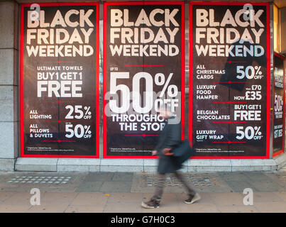 Les gens marchent devant des affiches annonçant les ventes du « Black Friday » sur Oxford Street, Londres. Banque D'Images