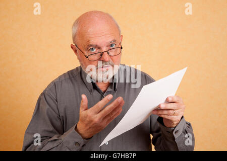 Un homme âgé, 59 ans, tenant une lettre, le projet de loi, l'air interrogateur Banque D'Images