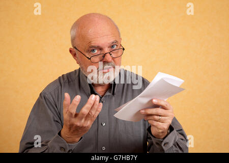 Un homme âgé, 59 ans, tenant une lettre, le projet de loi, l'air interrogateur Banque D'Images