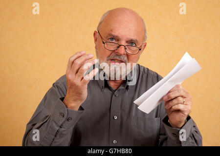 Un homme âgé, 59 ans, tenant une lettre, le projet de loi, discuter, expliquer Banque D'Images