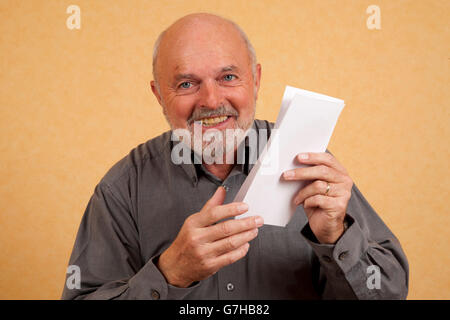 Un homme âgé, 59 ans, tenant une lettre, le projet de loi, à rire, heureux Banque D'Images
