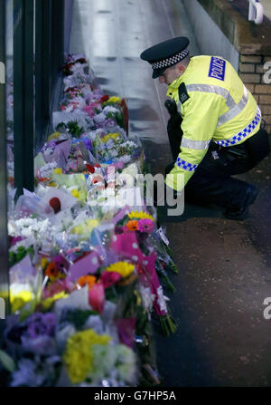 Un policier regarde les fleurs près de la scène à George Square, à Glasgow, où un camion-benne s'est écrasé dans un groupe de piétons qui a laissé six morts. Banque D'Images