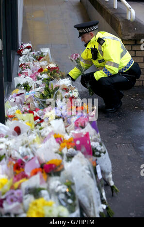 Un policier place des fleurs près de la scène à George Square, à Glasgow, où un camion-benne s'est écrasé sur un groupe de piétons qui a fait six morts. Banque D'Images