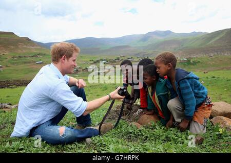 Le Prince Harry montre aux enfants une photo qu'il a prise avec un appareil photo Fuji X100s lors d'une visite à une école de nuit de garçon de troupeau construite par Sentebale à Mokhotlong, au Lesotho. Banque D'Images