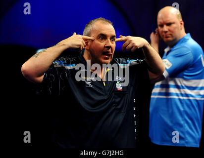 Phil Taylor réagit après avoir remporté la sixième série lors de son match avec Vincent van der Voort lors du championnat du monde des fléchettes William Hill à Alexandra Palace, Londres. Banque D'Images