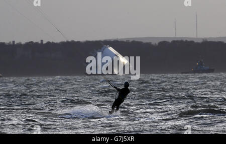 Un kite surfeur fait le maximum de vents forts près du porte-voiture Hoegh Osaka, Ce qui a été délibérément enchaché sur le banc de sable de Bramble Bank, près de Southampton, samedi dernier, est ancré à un endroit à trois miles à l'est, appelé Alpha Anchorage près de Lee-on-the-Solent, car les conditions météorologiques sont trop dangereuses pour que les salves commencent à pomper 3,000 tonnes d'eau à bord du navire. Banque D'Images