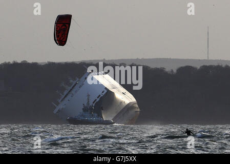 Un kite surfeur fait le maximum de vents forts près du porte-voiture Hoegh Osaka, Ce qui a été délibérément enchaché sur le banc de sable de Bramble Bank, près de Southampton, samedi dernier, est ancré à un endroit à trois miles à l'est, appelé Alpha Anchorage près de Lee-on-the-Solent, car les conditions météorologiques sont trop dangereuses pour que les salves commencent à pomper 3,000 tonnes d'eau à bord du navire. Banque D'Images