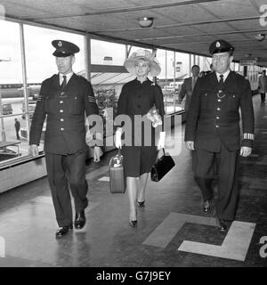 Escortée par deux policiers de l'aéroport, Marilyn (Mandy) Rice-Davies, témoin de 18 ans dans l'affaire Stephen Ward, se rend à l'avion lorsqu'elle quitte l'aéroport de Londres pour Palma, Majorque. Banque D'Images