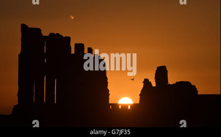 Le soleil se lève pour la dernière fois en 2014 sur le Prieuré de Tynemouth sur la côte nord-est. Banque D'Images