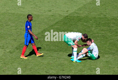 République d'Irlande est Seamus Coleman (à droite) et John O'Shea abattus après le dernier coup de sifflet que l'avion de Patrice Evra (à gauche) au cours de la marche se serrer la main pendant la série de 16 match au Stade de Lyon, Lyon. Banque D'Images