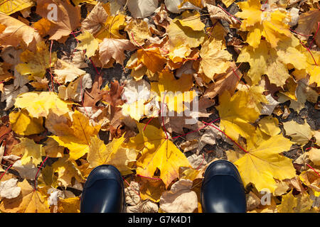 Bottes sombres sur un trottoir en automne Banque D'Images