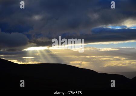 Vue depuis la route sur le ski de Glenmore Cairngorm Mountain range avec le soleil percer les nuages dans la distance Banque D'Images