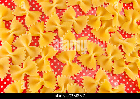 Pâtes farfalle papillon non cuites sur red dotted background Banque D'Images