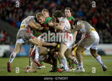 Les rabbitohs du sud de Sydney Tom Burgess sont affronté par James Roby de St Helens (à gauche) Joe Greenwood (à l'arrière) et Kyle Amor (au centre) lors du match de la série World Club à Langtree Park, à St Helens. Banque D'Images