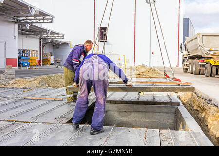 Les travailleurs sont mis en place à la dalle de béton de l'édifice souterrain de l'assemblée. Banque D'Images