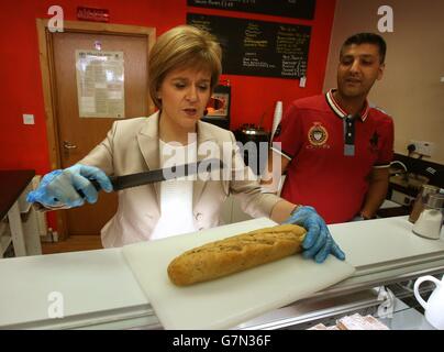 Le chef du SNP et Premier ministre Nicola Sturgeon fait un sandwich dans le bar Quick Bite Sandwich à Glasgow avec la propriétaire Aftab Baig alors qu'elle fait campagne avec des activistes locaux. Banque D'Images