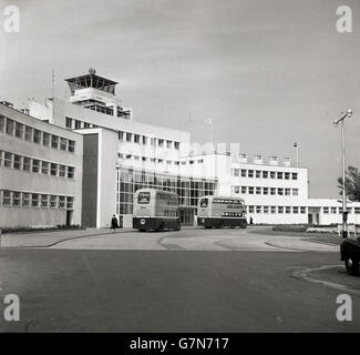 Dans les années 1950, deux bus à impériale de la compagnie aérienne nationale irlandaise Aer Lingus, stationnés devant l'entrée du terminal de l'aéroport de Dublin. Ouvert en 1941 et conçu par des architectes dirigés par Desmond FitzGerald à l'Office des travaux publics, sa conception était basée sur celle des paquebots de luxe de l'époque. L'aéroport était connu à cette époque comme l'aéroport de Collinstown, ayant été développé pour l'aviation civile en 1937 à partir de l'ancien aérodrome de Collinstown, qui avait été la base du corps royal britannique de vol, le prédécesseur de la RAF. Le premier vol y avait eu lieu en 1940. Banque D'Images