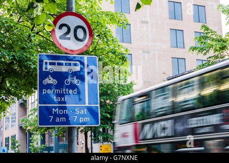 Un bus conduit au-delà d'un signe pour un bus lane et un 20mph vitesse en centre-ville de Belfast. Banque D'Images