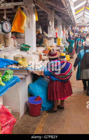 Courte femme péruvienne d'acheter les haricots secs et les pommes de terre blanches au marché de San Pedro de Cusco Banque D'Images