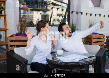 Happy business couple at outdoor restaurant selfies Banque D'Images