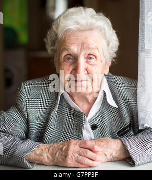 Portrait d'une femme âgée assise à la table. Banque D'Images