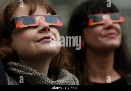 Les gens regardent alors qu'ils attendent une pause dans les nuages pour apercevoir l'éclipse partielle du soleil depuis la place principale de Trinity College de Dublin, en Irlande. Banque D'Images