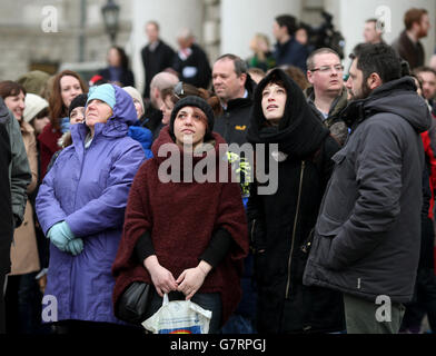 Les gens regardent alors qu'ils attendent une pause dans les nuages pour apercevoir l'éclipse partielle du soleil depuis la place principale de Trinity College de Dublin, en Irlande. Banque D'Images