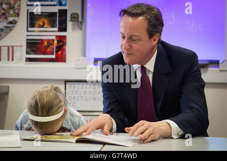 Le Premier ministre David Cameron donne une leçon de lecture à l'école primaire catholique du Sacré-cœur de Westhinton, près de Bolton, avec Lucy Howarth, âgée de six ans, pendant la campagne électorale générale. Banque D'Images